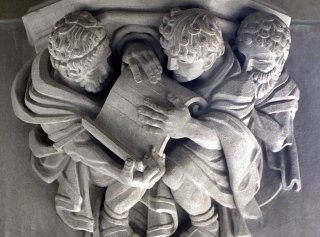 Stone Carving of Three Men Looking at a Scroll Sterling Memorial Library